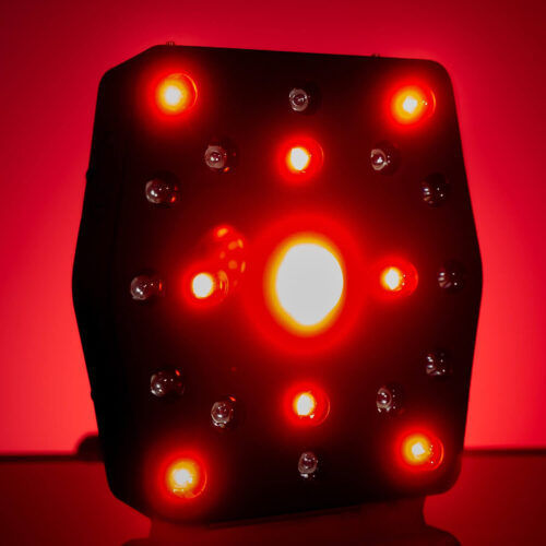 Close-up of a black helmet-like device with multiple red LED lights glowing against a red background.