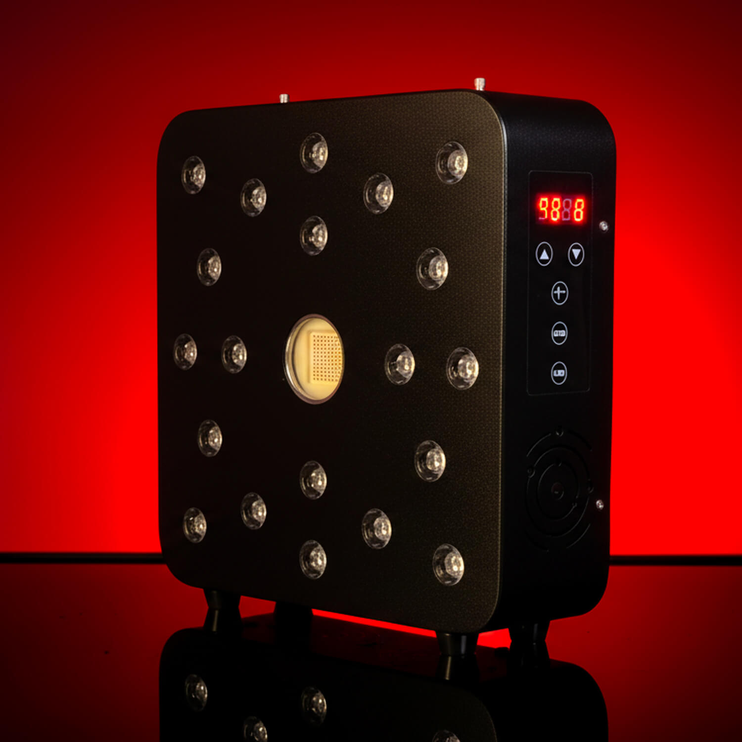 Large black rectangular device with numerous round LED lights on its front, side panel showing a red digital display against a red background (cosmetic/therapy equipment).