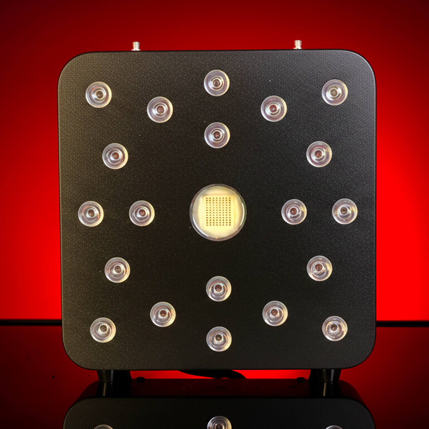 Front view of a black square electronic panel with evenly spaced round LEDs around a central square chip, red background.