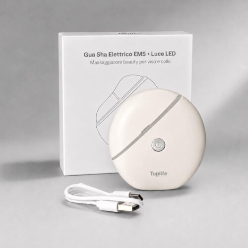 Round white facial massager with an on/off button and USB cable placed beside its box labeled Gua Sha Elettrico EMS Luce LED (LED/EMS beauty device).