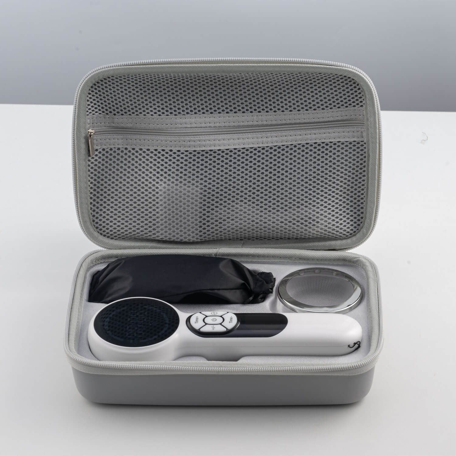 Portable grey travel case opened to reveal a handheld massage wand with a round head and its remote control inside the case