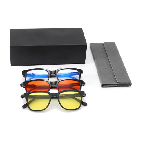 Three pairs of sunglasses with blue, red, and yellow lenses placed in front of a black box and gray foldable case for sale/retail display.